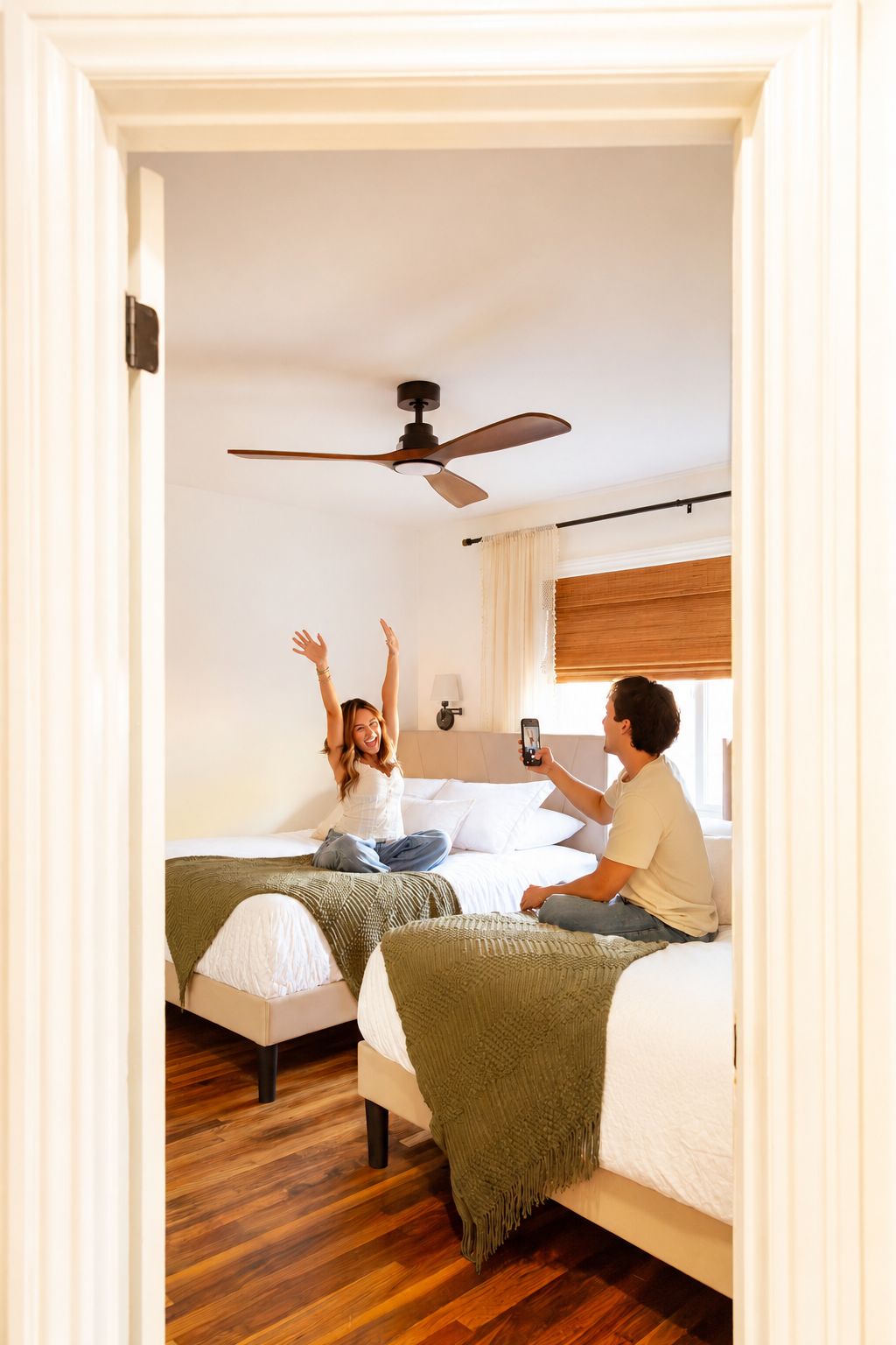 Un dormitorio con dos camas, ventilador de techo y ventana con cortinas.