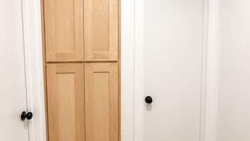 Un couloir doté d’un plancher en bois et de murs blancs, avec une porte double et une porte simple.