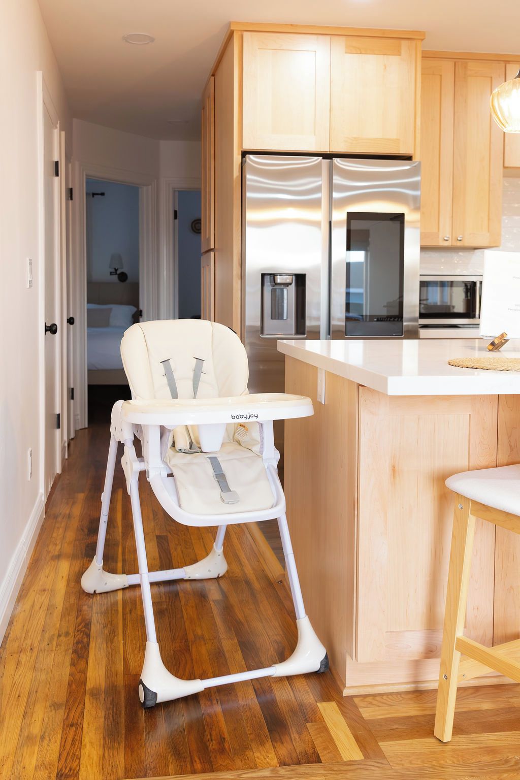 Eine moderne Küche mit Holzausstattung, einem weißen Kühlschrank und einem hochaugestellten Kinderstuhl.