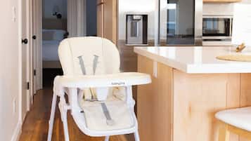 Una cucina moderna con mobili in legno, un frigorifero bianco e una seggiolina da pappa.