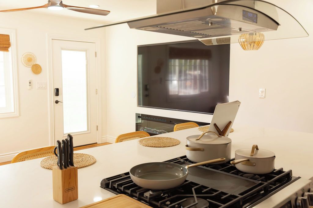 Une cuisine moderne dotée d’un îlot central, d’une cuisinière et d’un téléviseur à écran plat fixé au-dessus de l’îlot.