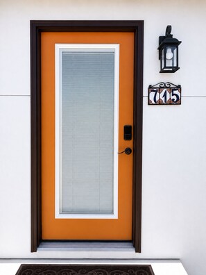 A door with a number plaque, a doorbell, and a wall-mounted light fixture. - Sleeps 8 • King Suite • 2 Queens (Chula Vista)