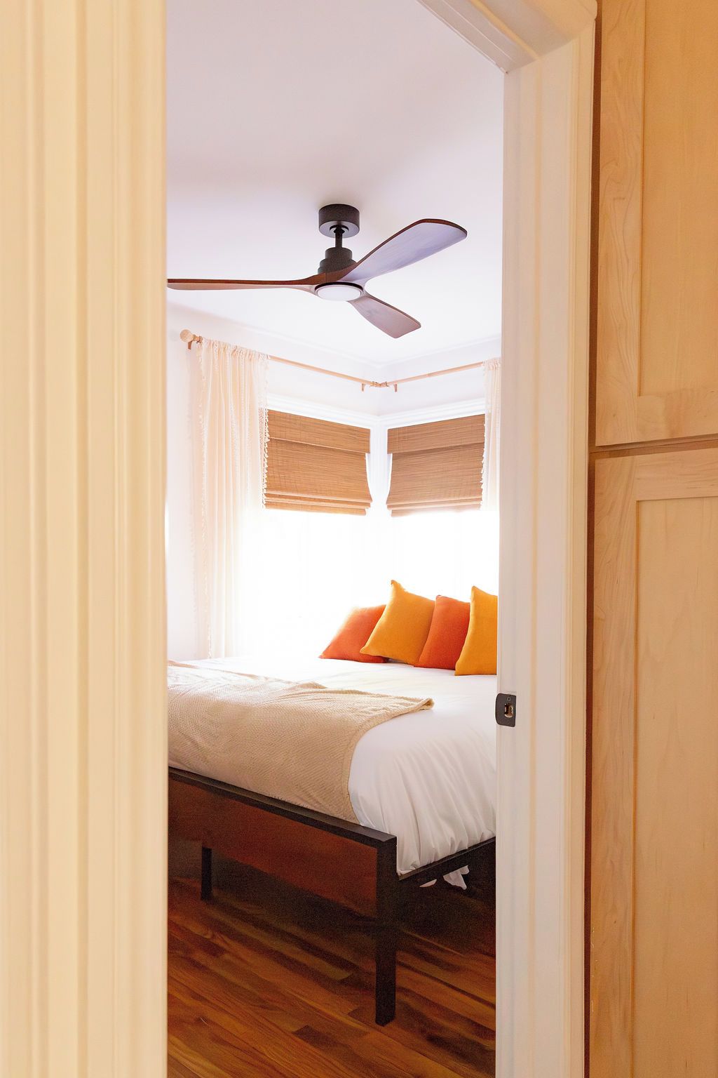 Une chambre à coucher avec un lit, un ventilateur de plafond et un plancher en bois.