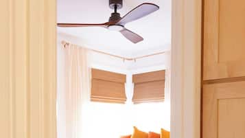 Une chambre à coucher avec un lit, un ventilateur de plafond et un plancher en bois.