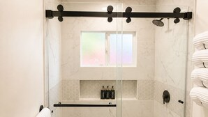 Un baño moderno con ducha de vidrio, inodoro y barra para toallas.
