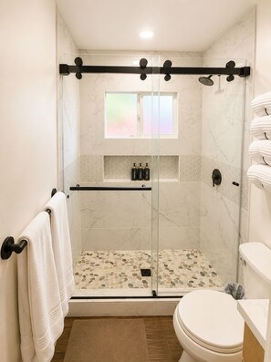 Ein modernes Badezimmer mit einer Duschkabine, einer Toilette und einem Handtuchhalter.