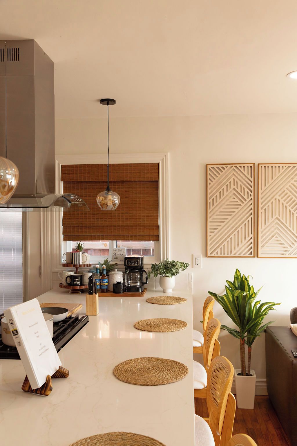 Una cocina moderna con una isla central, una cafetera y una planta en maceta.