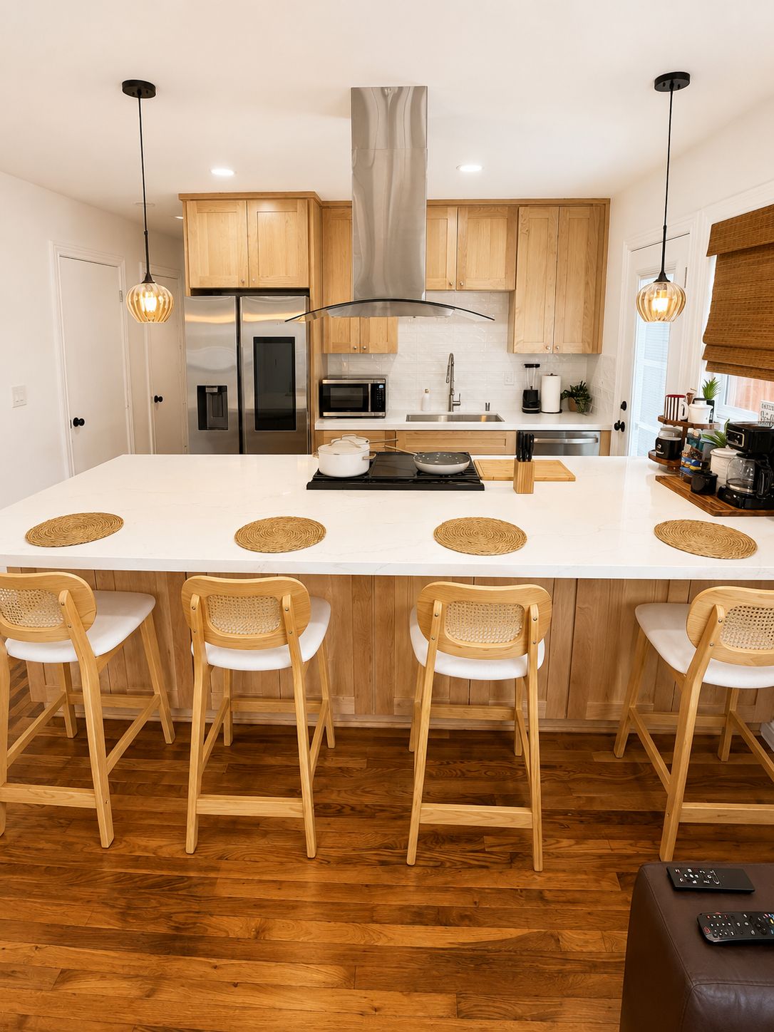 A modern kitchen with a central island, wooden chairs, and a bar area.