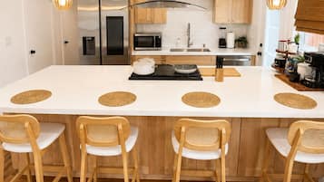 A modern kitchen with a central island, wooden chairs, and a bar area.