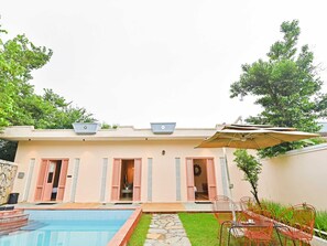 A building with a swimming pool, outdoor seating, and a covered patio area. - Suite With Garden View Parijat Villas (Udaipur)