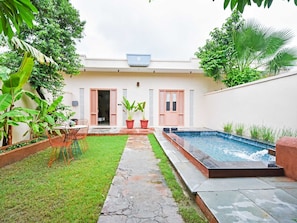 A residential property with a swimming pool, a small lawn, and a patio area.