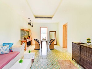 A hotel room with a kitchenette, a dining area, a sofa, a small table, and a cabinet.