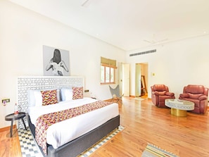 A spacious bedroom with a large bed, a chair, and a small table.