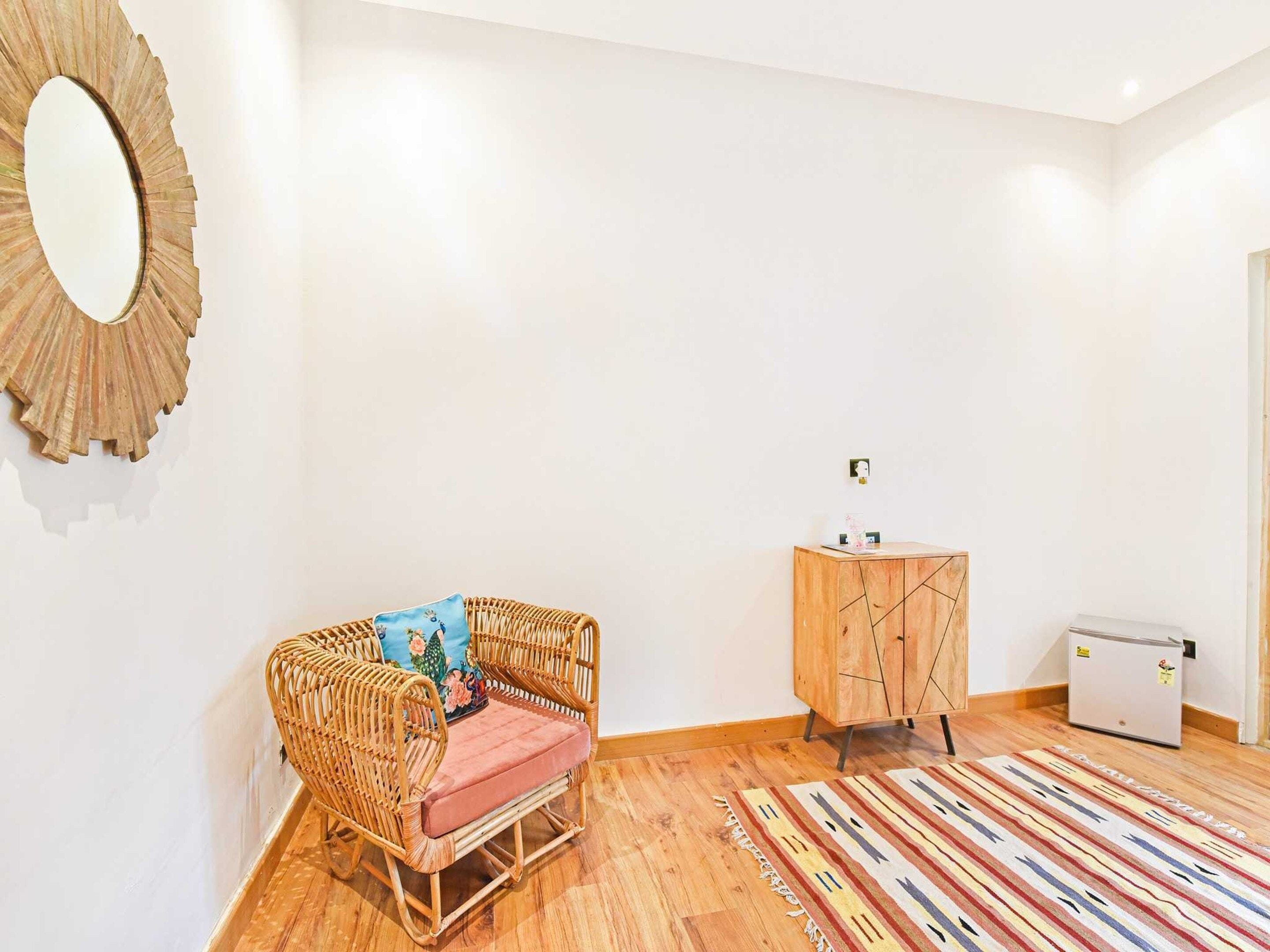 A room with a wicker sofa, a wooden cabinet, and a refrigerator.