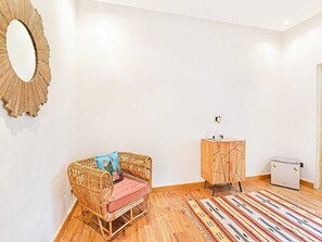 A room with a wicker sofa, a wooden cabinet, and a refrigerator. - Suite With Garden View Parijat Villas (Udaipur)