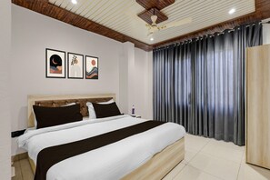 Ein Hotelzimmer mit Bett, Kopfteil, Deckenventilator und Vorhängen.