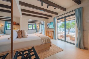 Een moderne slaapkamer met een groot bed, uitzicht op het buitengebied en een eettafel.