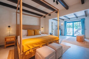 A four-poster bed with a yellow bedspread, a wooden nightstand, a bedside lamp, and a large window with a view of the outdoors. - OceanView Villa Steps from Beach| Bougainvillea (Noord)
