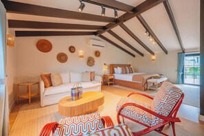 Ein geräumiger Raum mit hoher Decke, einem Bett, einem Sofa, einem roten Sessel und einem kleinen Tisch.