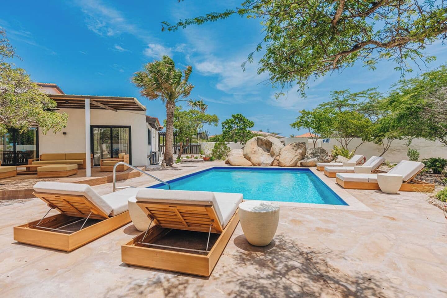 Piscina com espreguiçadeiras e uma parede de pedra.