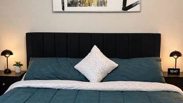 A bed with a teal comforter, a white zigzag pillow, and a black headboard.