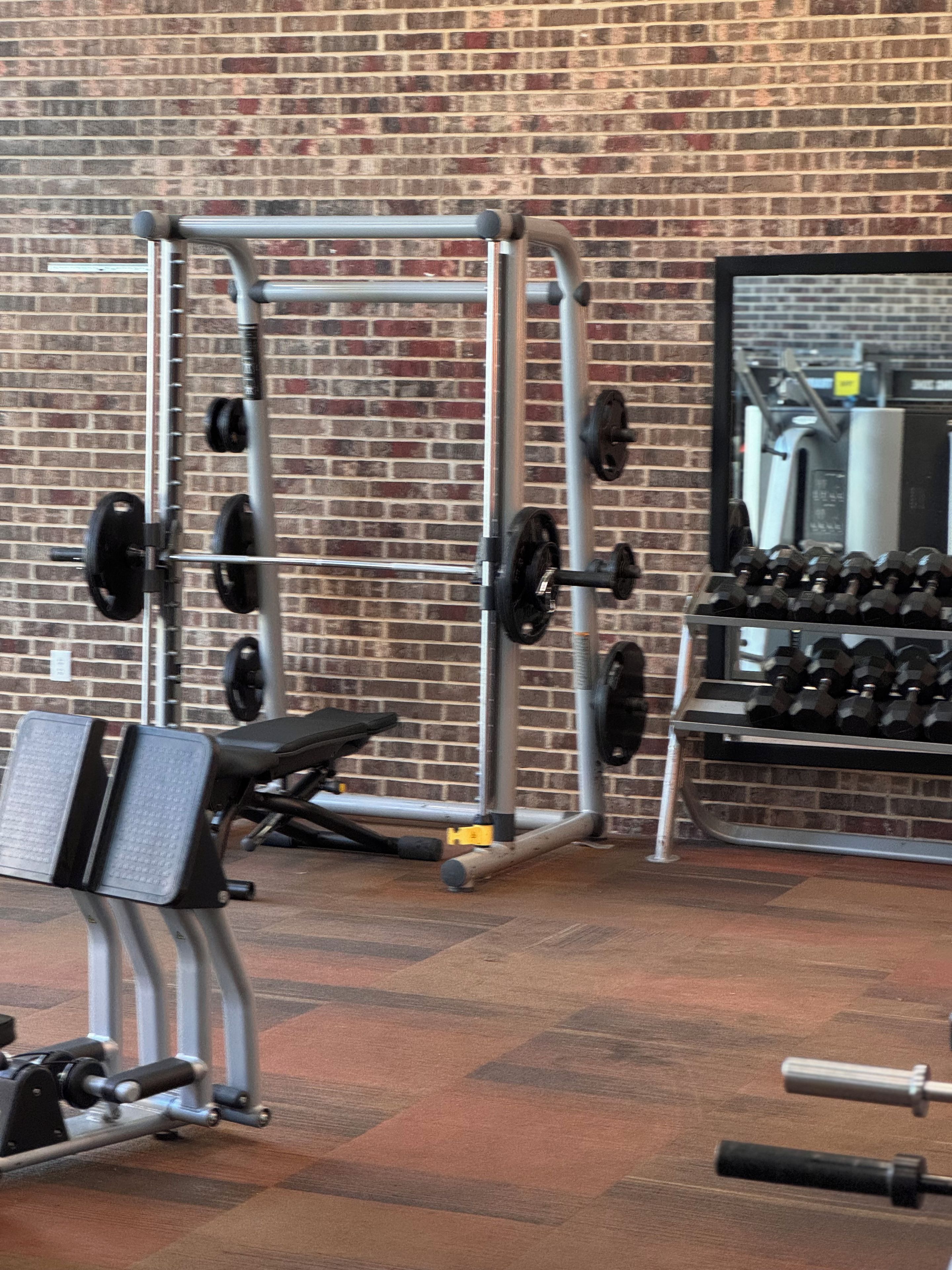 A gym with a brick wall, weightlifting equipment, and a bench.