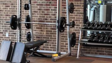 A gym with a brick wall, weightlifting equipment, and a bench.