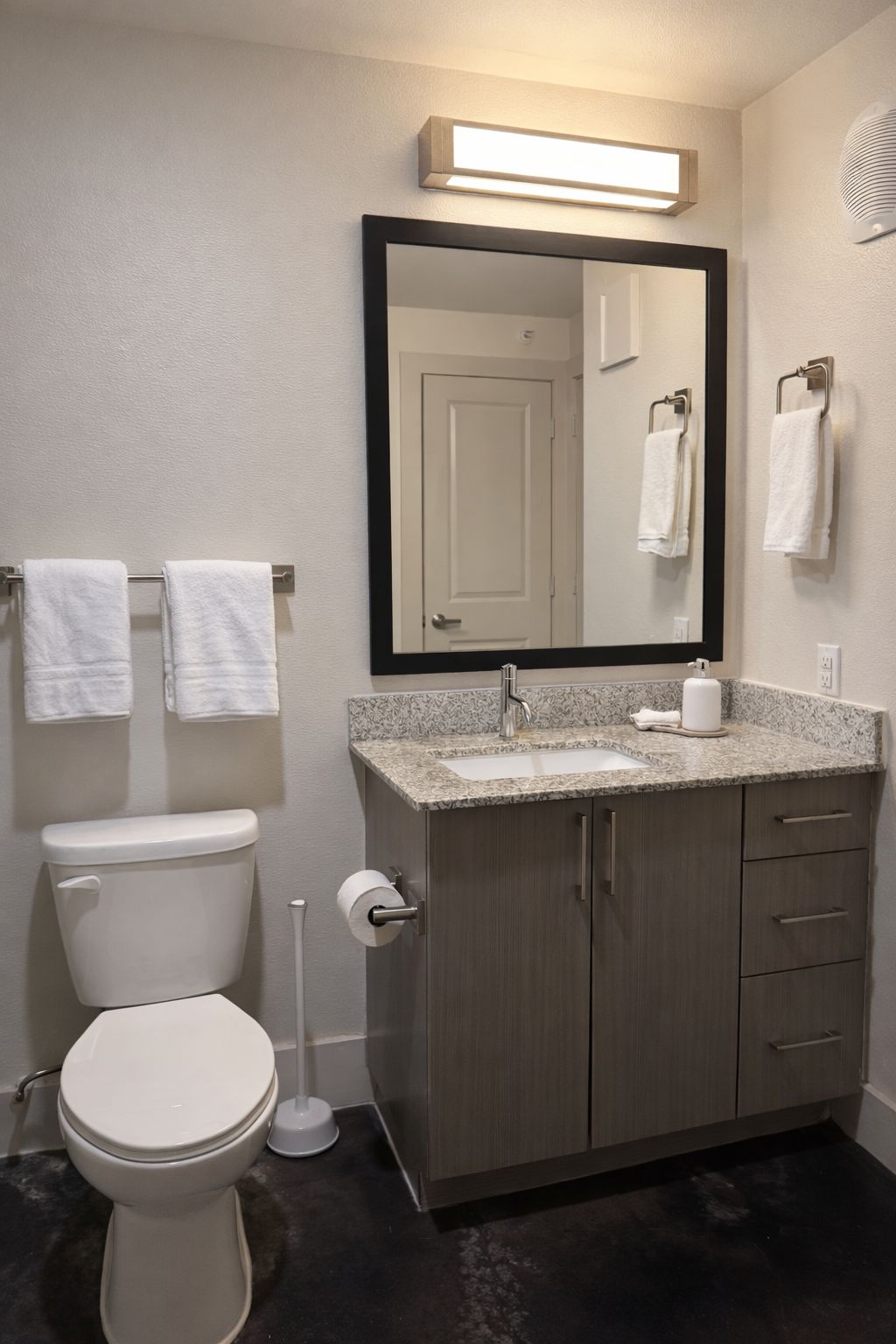 A bathroom with a toilet, sink, mirror, and towel rack.