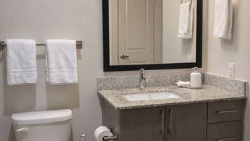 A bathroom with a toilet, sink, mirror, and towel rack.
