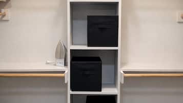 Une étagère blanche avec des boîtes de rangement noires, placée contre un mur de couleur claire.