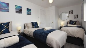 A hotel room with two beds, a ceiling fan, a round mirror, and artwork on the walls. - Beautiful 3BRHome with a large garden in Colchester (Colchester)