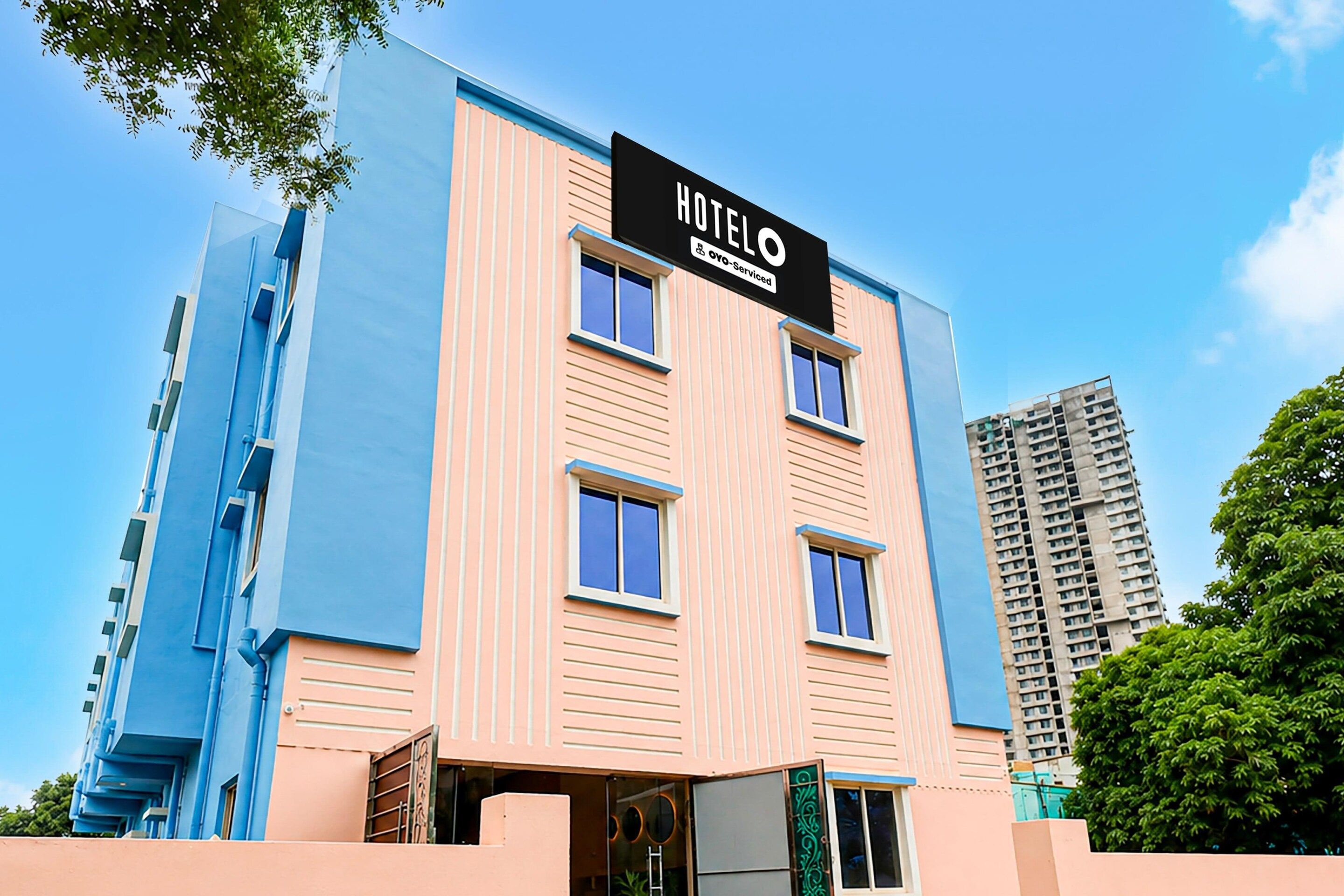 A hotel building with a sign reading 'HOTEL OYO-Serviced' and a modern architectural design.
