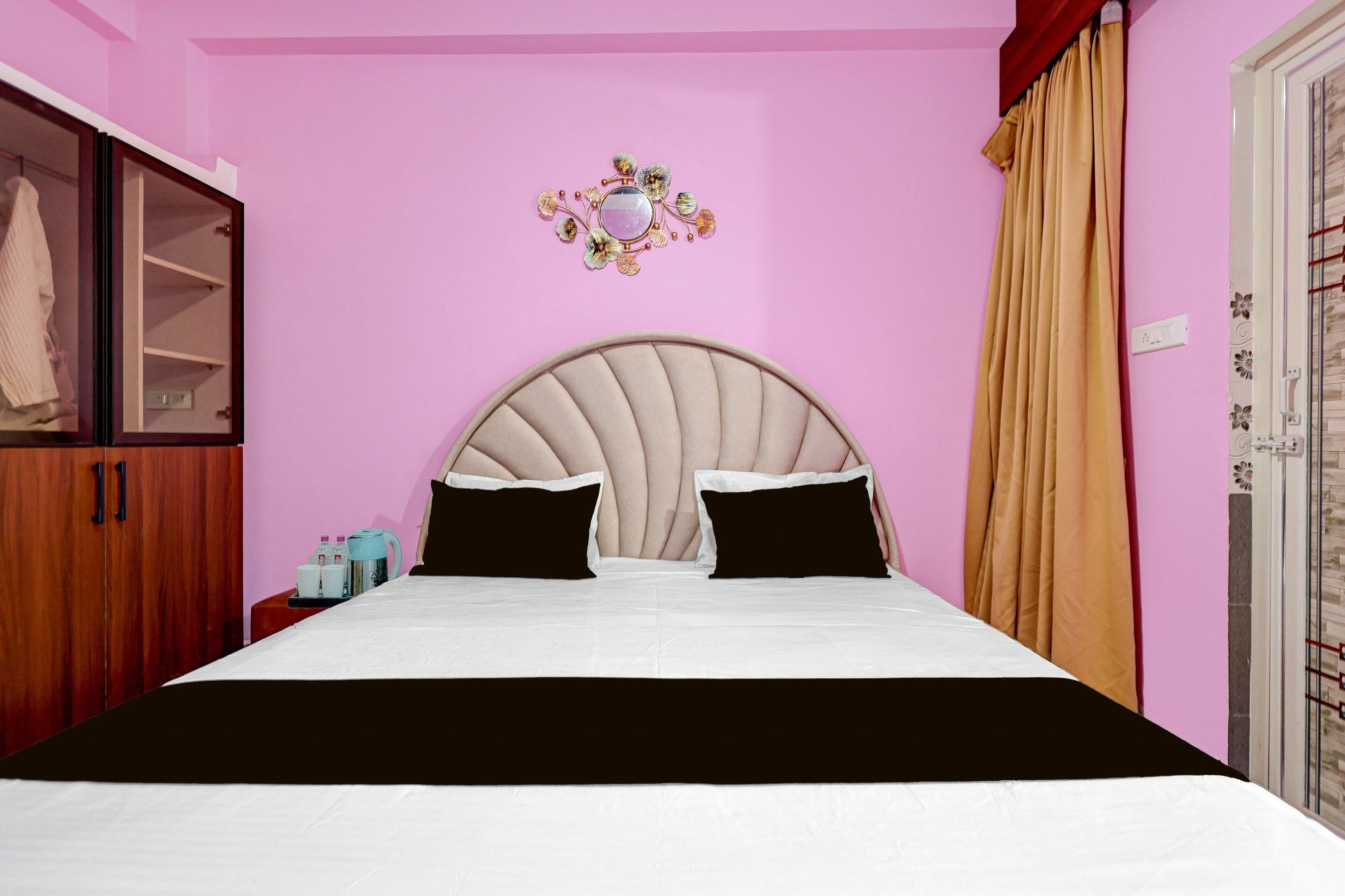 Une chambre à coucher avec un lit, une armoire, un miroir et une fenêtre avec des rideaux.