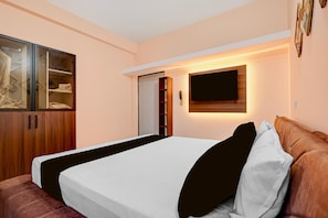 A bedroom with a bed, a wardrobe, and a television mounted on the wall. - Classic Bhubaneswar New Station Road (Bhubaneshwar)