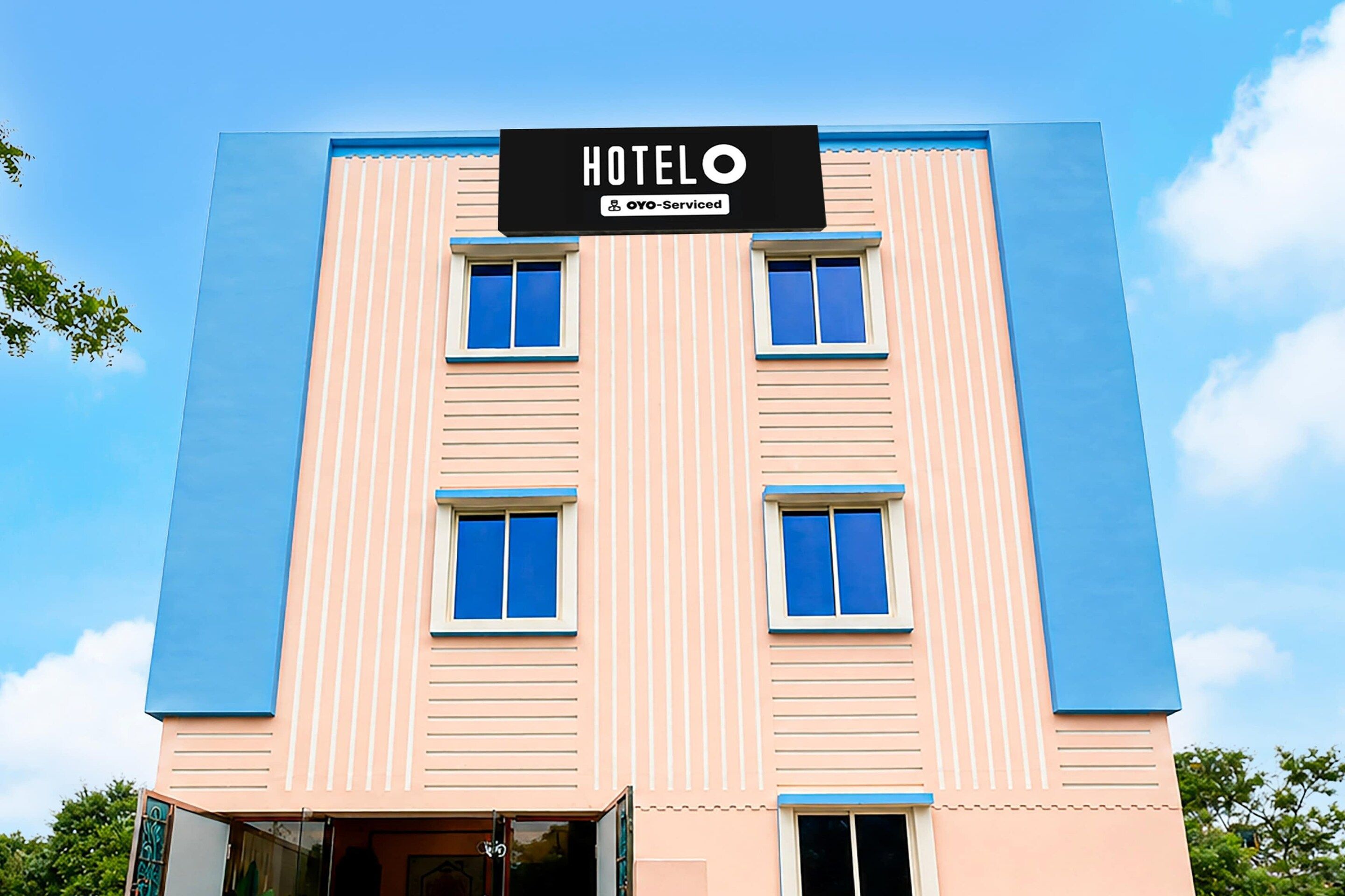 A hotel building with a sign reading 'HOTELO' and 'OYO-Serviced' indicating a partnership.