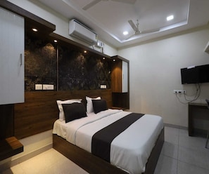 Un dormitorio moderno con una cama grande, armario empotrado, aire acondicionado, ventilador de techo y televisor de pantalla plana.
