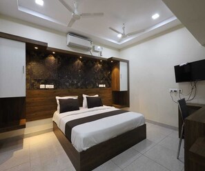 Un dormitorio moderno con una cama grande, cabecero de madera empotrado, iluminación empotrada y ventilador de techo.