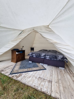 Ein Zelt mit einem Bett, einem Schminktisch und einem Teppich.