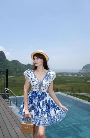 A person standing by a pool with a view of a landscape. - The Eden Cat Ba (Cat Hai)