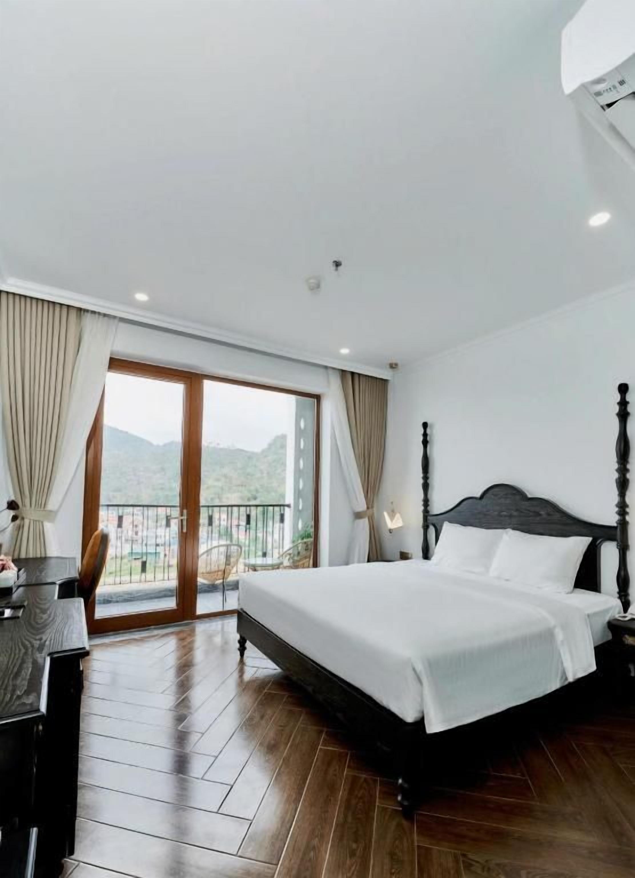 Un dormitorio con una cama grande, un escritorio y un balcón con vistas a las montañas.