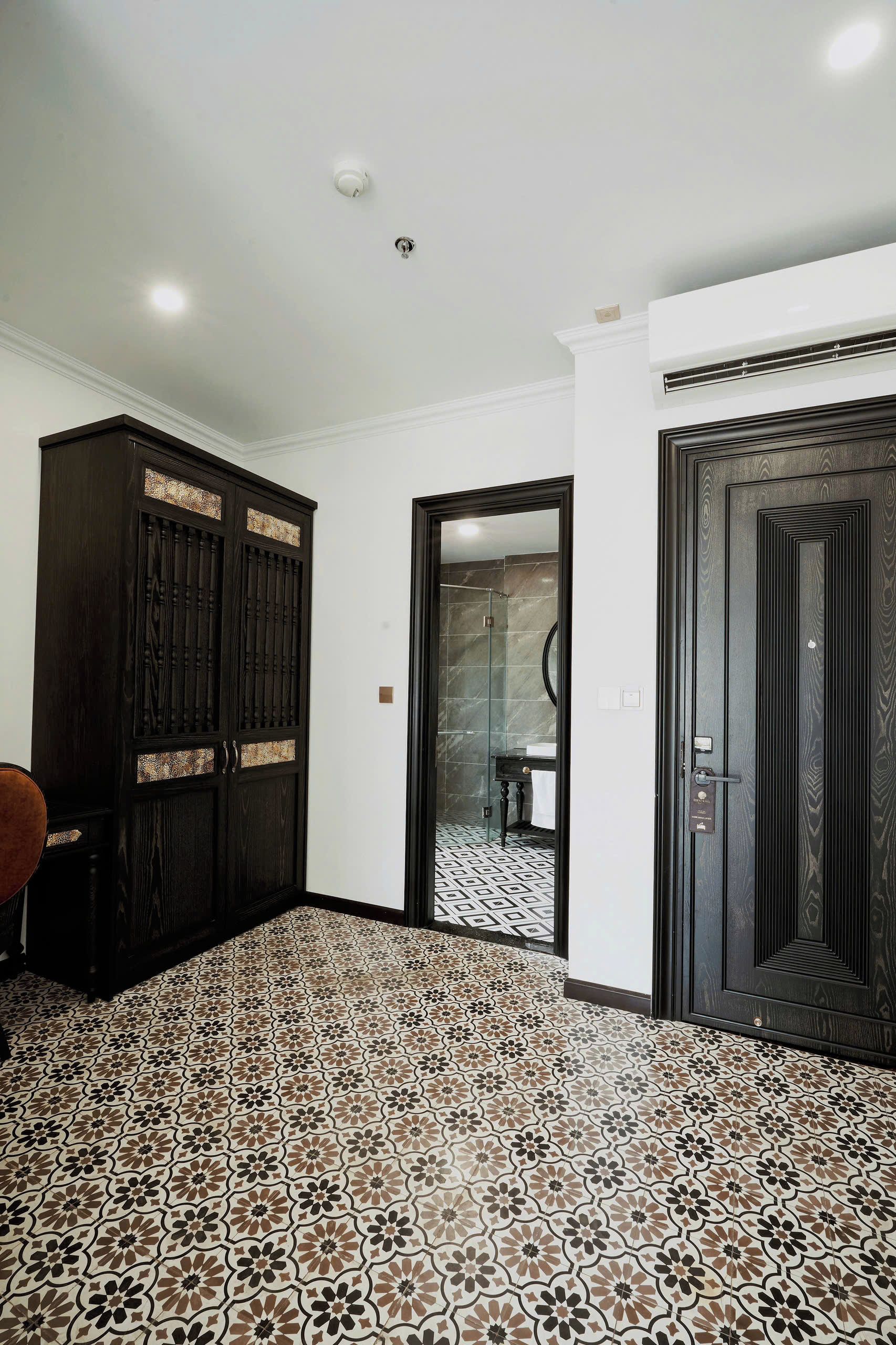 A hallway with patterned floor tiles, a dark wooden wardrobe, and a door with a keyhole.
