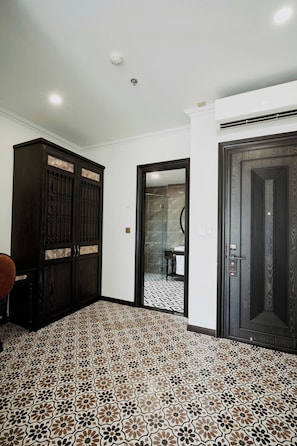 Un pasillo con baldosas de diseño, un armario de madera oscura y una puerta con cerradura.