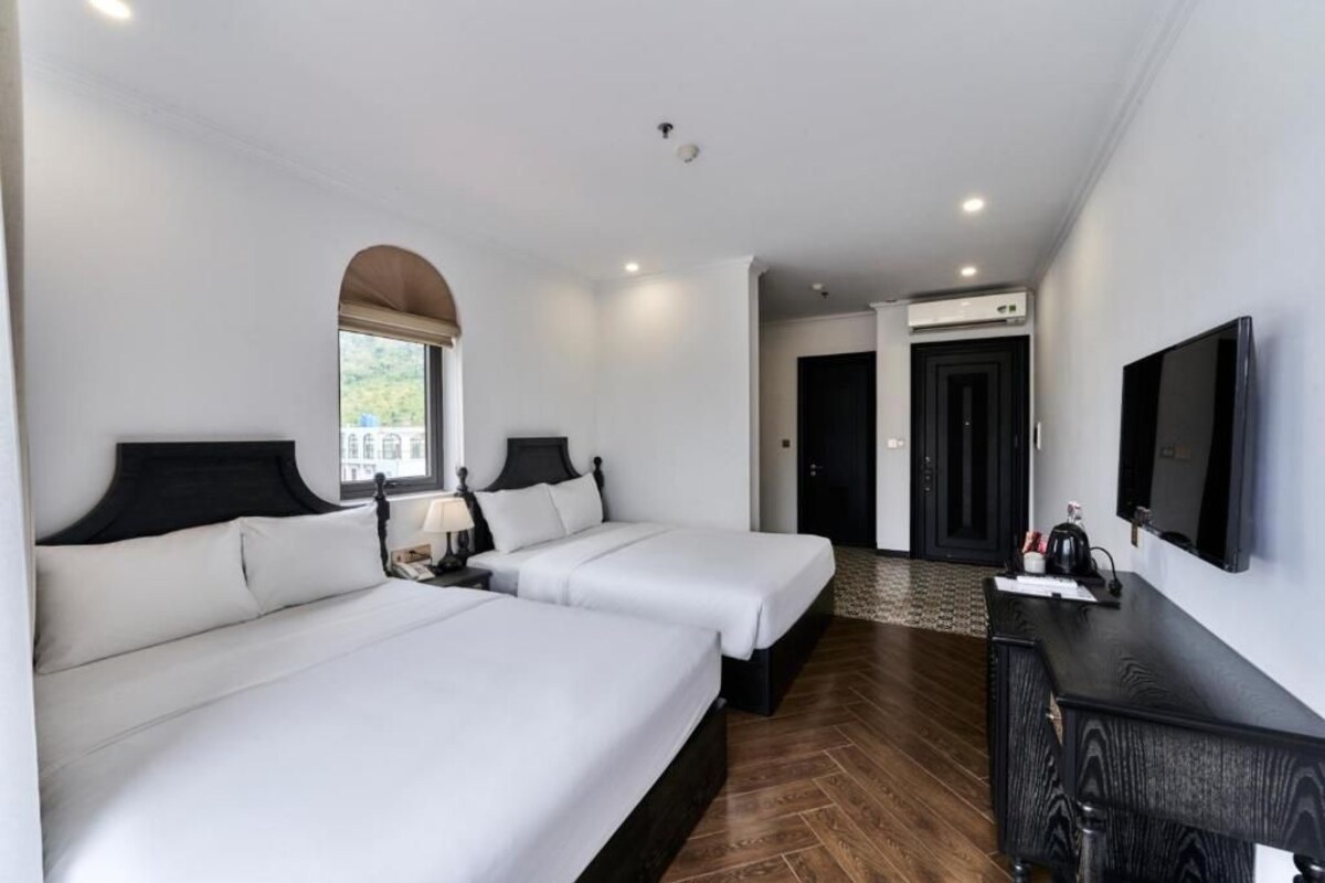 Een hotelkamer met twee bedden, een televisie, een bureau en een boogvenster.