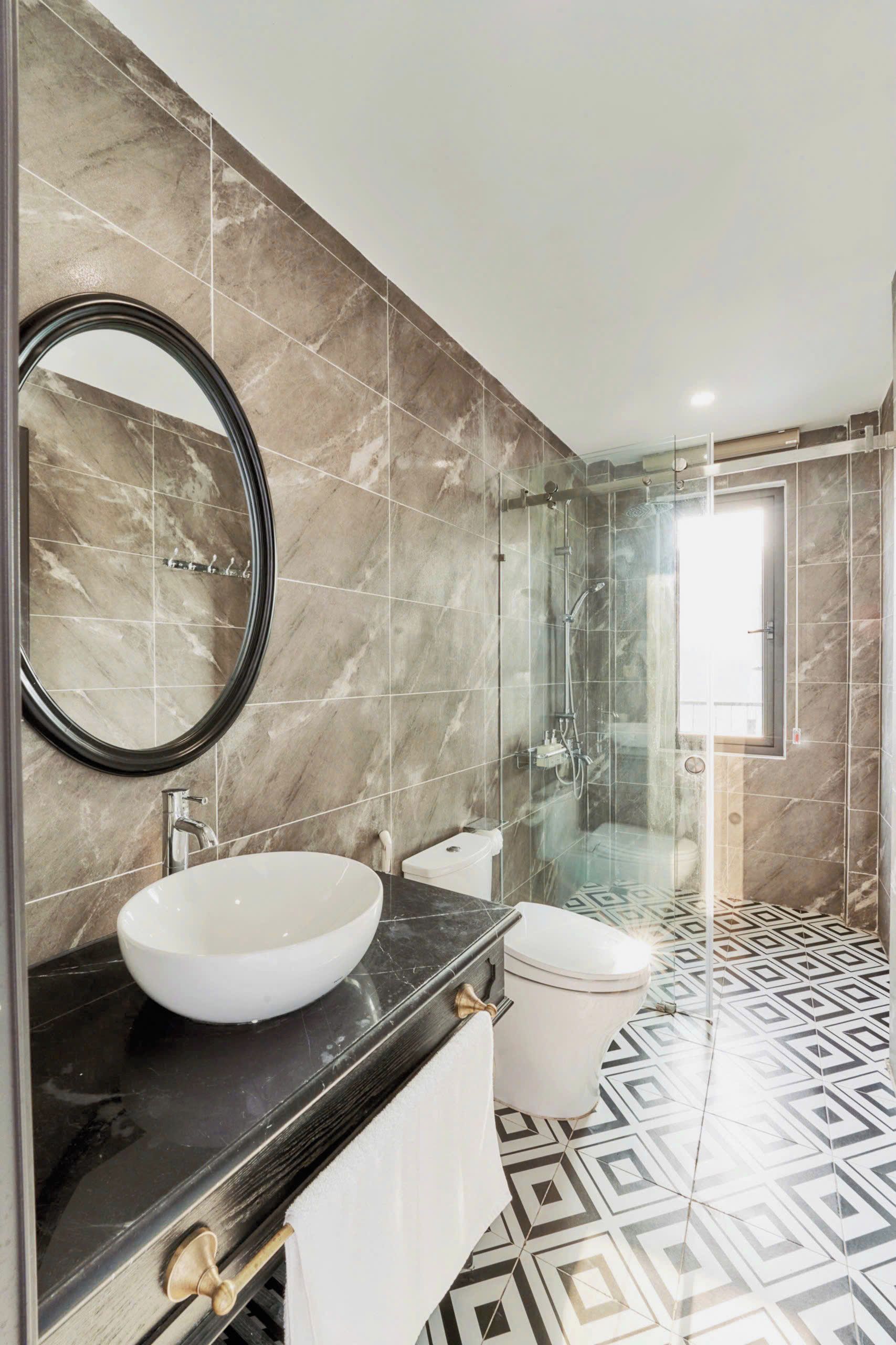 A modern bathroom with a large oval sink, a toilet, a glass-enclosed shower, and a mirror.
