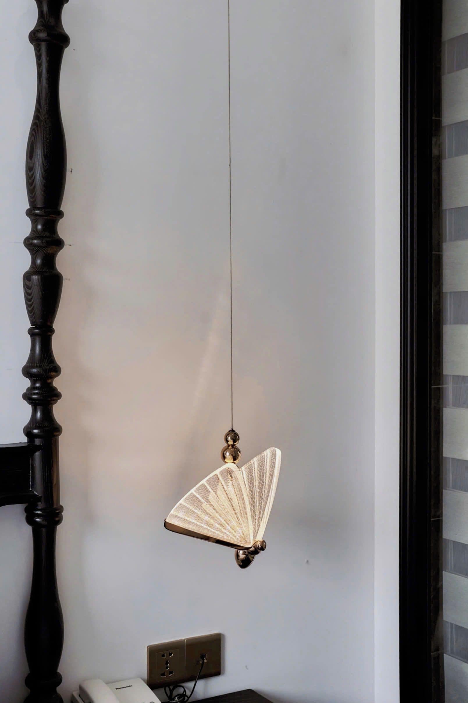 A room with a dark wooden chair, a wall-mounted light fixture, and a power outlet.