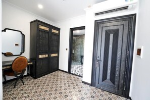 A room with a desk, chair, wardrobe, and a door. - The Eden Cat Ba (Cat Hai)