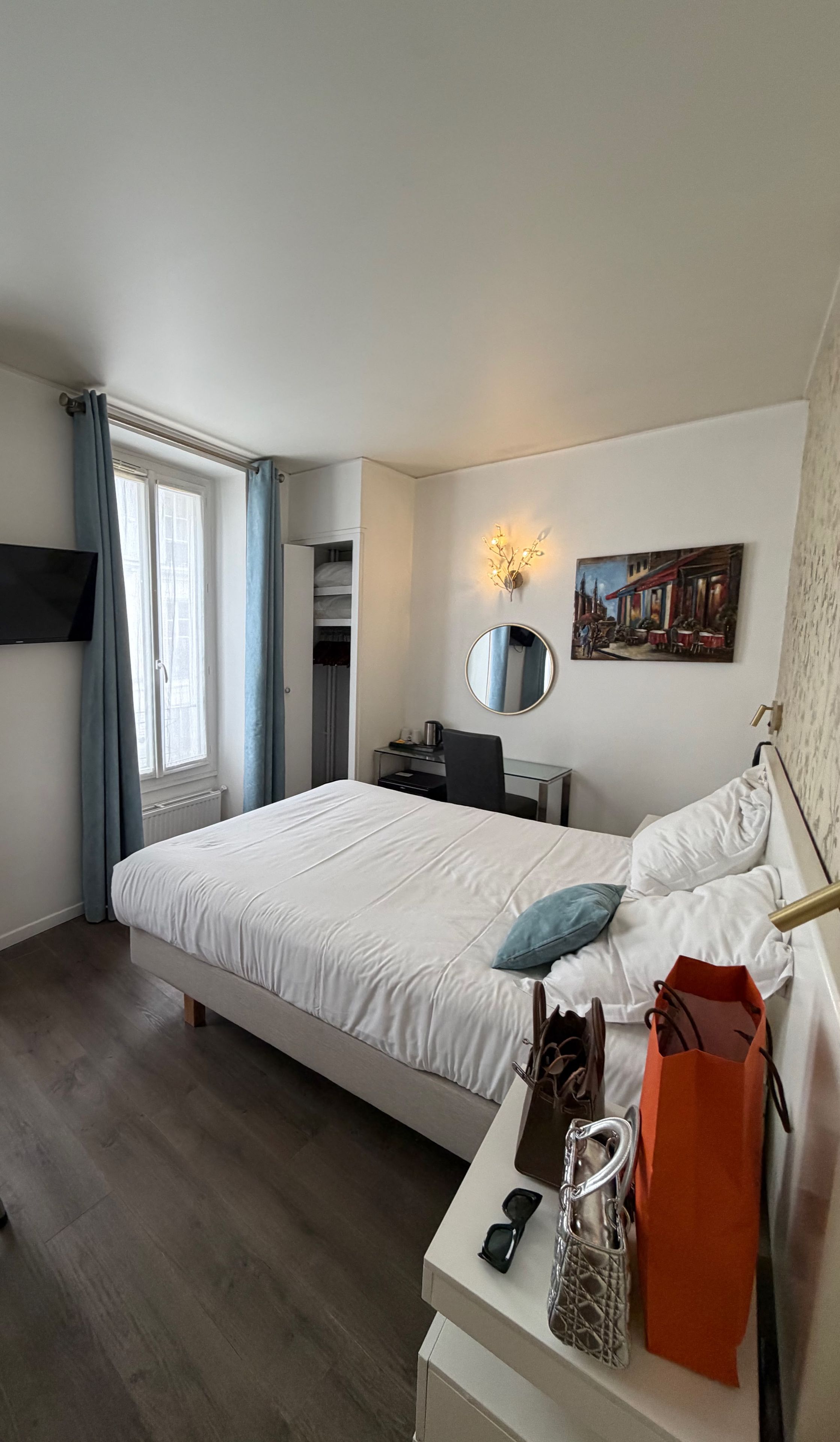 Una habitación de hotel con cama, escritorio, silla y un cuadro en la pared.