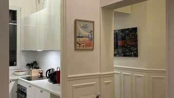 Una cocina moderna con armarios blancos, piso de baldosas blanco y negro y un radiador.