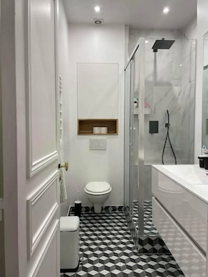 A modern bathroom with a toilet, a shower, and a sink. - Vrbo Property (Paris)