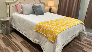 A bed with a white bedspread and a yellow-orange patterned throw blanket. - Updated near Death Valley, large outdoor space (Amargosa Valley)